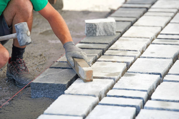 Industrial worker installing pavement rocks, cobblestone blocks on road pavement
